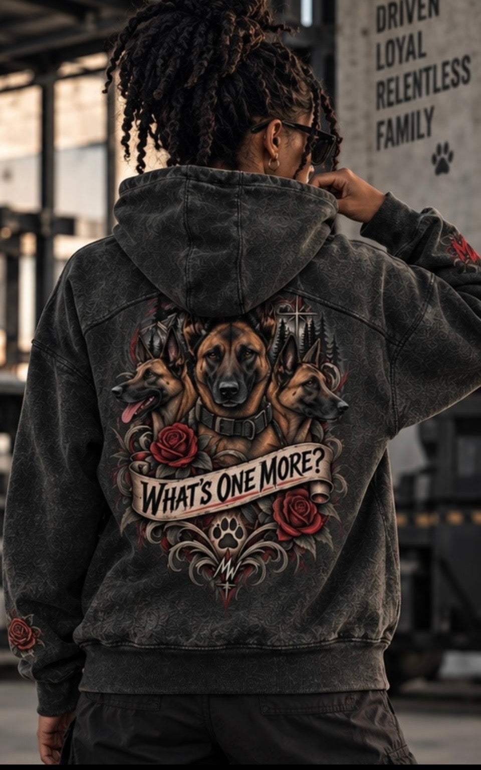 A person shown from behind wearing a faded black hooded sweatshirt with a large graphic print on the back featuring three dogs, red roses, and the text 'WHAT'S ONE MORE?'.