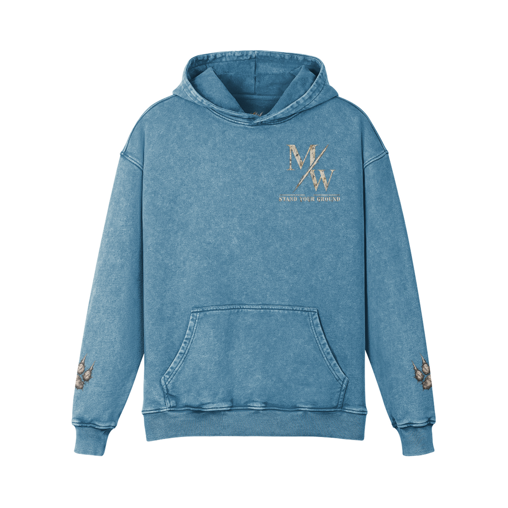 A blue acid-wash pullover hoodie with a gold foil 'MW' logo and 'STAND YOUR GROUND' text on the left chest, featuring embroidered butterfly details on both sleeves.